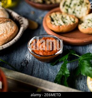 Eine Glasschale mit einer veganen Version der typisch spanischen Sobrasada, aus roter Süßkartoffel, auf einem grauen rustikalen Holztisch neben einem anderen k Stockfoto