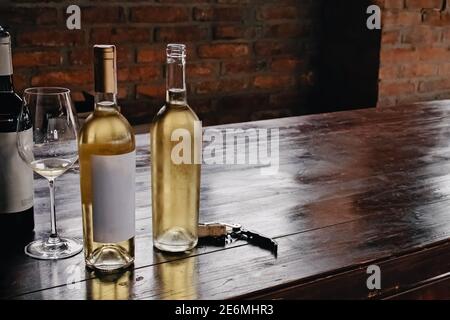 Flaschen mit Weißwein auf rustikalem Holztisch Stockfoto