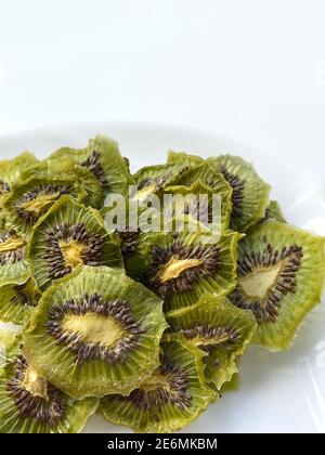 Dehydrierte Kiwi-Scheiben mit Zucker isoliert auf weißem Teller Stockfoto