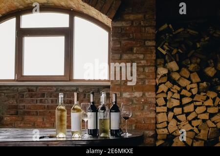 Flaschen mit Weiß- und Rotwein auf rustikalem Holztisch Stockfoto