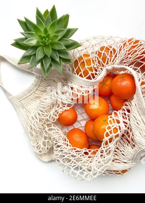 Mesh-Beutel von frischen Orangen gesunde Zitrusfrüchte von auf weißem Hintergrund. Flach liegend, Draufsicht. Stockfoto