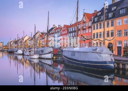 Sonnenaufgang an der farbenfrohen Uferpromenade des Nyhavn Canal (New Harbour), einem Unterhaltungs- und Touristenviertel von Kopenhagen, Dänemark im Morgengrauen mit dekoriert Stockfoto