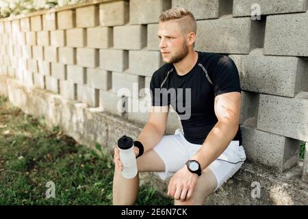 Durstiger Läufer, der eine Pause und Trinkwasser nimmt Stockfoto