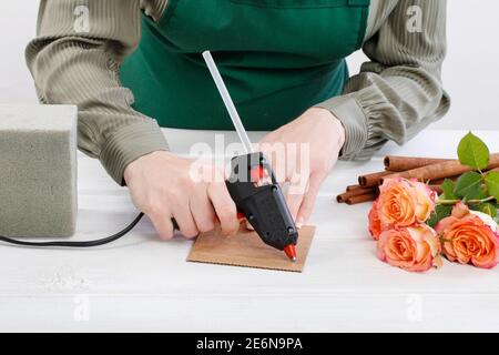 Florist bei der Arbeit: Wie man Blumenarrangement mit Rosen und Zimtstangen machen. Schritt für Schritt, Tutorial. Stockfoto