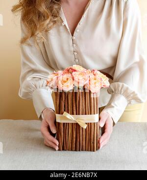 Florist bei der Arbeit: Wie man Blumenarrangement mit Rosen und Zimtstangen machen. Schritt für Schritt, Tutorial. Stockfoto