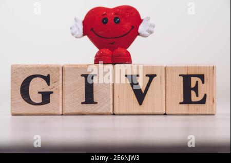 Wort GEBEN buchstabiert auf Holzklötze. GEBEN Sie Wort auf Holzblöcke auf Holztisch geschrieben. Konzept des Teilens, Gebens. Stockfoto