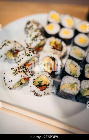 Set aus Sushi-Brötchen, Soße, Wasabi und Hand mit Essstäbchen auf dunklem Hintergrund. Draufsicht. Flach liegend. Japanisches Essen Stockfoto