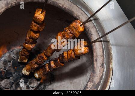 Drei Spieße gefüllt mit Fleisch Kochen in einem Tandoor Ofen In der Küche eines indischen Restaurants Stockfoto