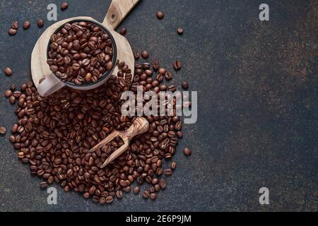 Kaffee geröstete Bohnen in der Tasse und in der Nähe verstreut, gemahlener Kaffee und Rohrzucker auf einem braunen Tischhintergrund. Draufsicht mit Platz zum Kopieren von Text. Stockfoto