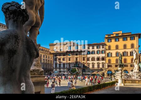 Blick auf den Platz Piazza della Signoria neben der Rückseite von Michelangelos David-Skulptur in Florenz. Die Menschen gehen zwischen dem Brunnen... Stockfoto