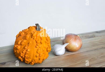 Auf dem Holztisch steht ein Kopf aus Zwiebel, Knoblauch und Orangenkürbis Stockfoto
