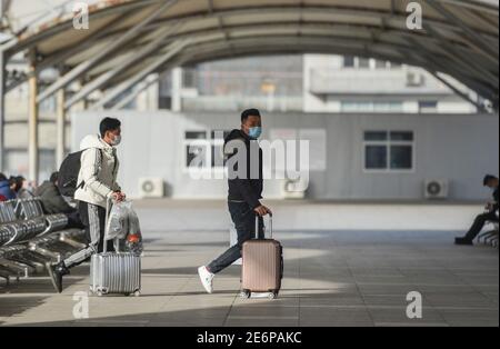 Fuyang, China. Januar 2021. Passagiere, die ihr Gepäck tragen, laufen durch den Bahnhof von Fuyang.als die Reisestrequenz des Frühlingsfestes begann, haben die Transportunternehmen die Maßnahmen verschärft, um das Wiederaufleben von COVID-19 (Coronavirus) Fällen zu verhindern, indem sie die Gesichtsmask für alle Passagiere im Bahnhof verpflichtend machen. Rund 1.15 Milliarden Passagierfahrten wurden während der 40-tägigen Reiseansturm erwartet, ein Rückgang gegenüber dem Vorjahr von 20 Prozent und mehr als 60 Prozent weniger als im Jahr 2019 nach Angaben des Ministeriums. Kredit: SOPA Images Limited/Alamy Live Nachrichten Stockfoto