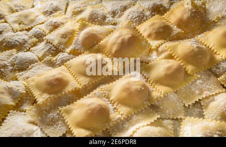 Rohe Ravioli mit Mehl, typisch italienische gefüllte Eiernudeln, Nahaufnahme, Draufsicht Stockfoto