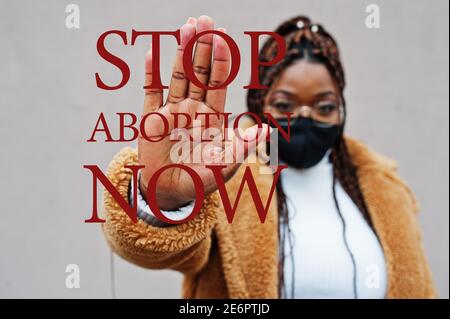 Stoppen Sie jetzt die Abtreibung. afroamerikanische Frau, tragen schwarze Gesichtsmaske zeigen Stop Hand Zeichen. Stockfoto