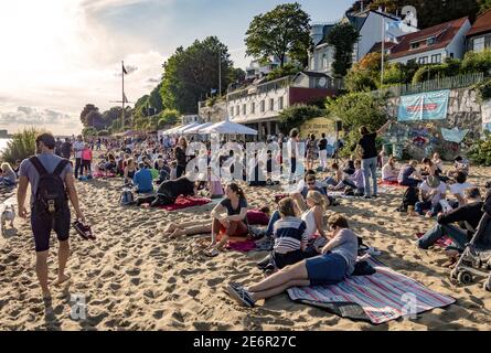 Einheimische und Touristen entspannen sich in der Sonne auf dem Sand Der Elbstrand an der Elbe gegenüber von Hamburg legt an Deutschland Stockfoto