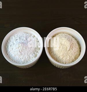 Schüssel mit weißem Mehl und EINE Schüssel mit Vollkornmehl Isoliert auf schwarzem Hintergrund Stockfoto
