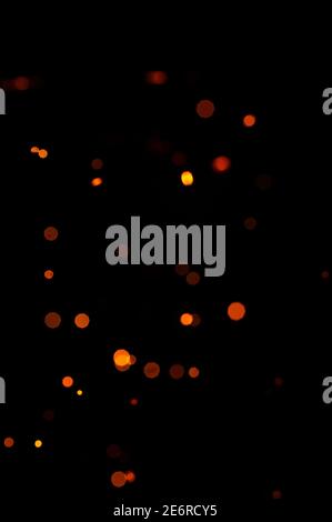 Orange Bokeh auf schwarzem Hintergrund, brennende und verschwommene Funken aus dem Feuer. Partikel brennender Glut fliegen und glühen isoliert am Nachthimmel 2021. Stockfoto