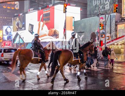 Zwei Pferde berittene Polizeibeamte Patroling in Times Square, Manhattan, New York City, USA. Animierte LED-Bildschirme und Plakatwände im Hintergrund Stockfoto
