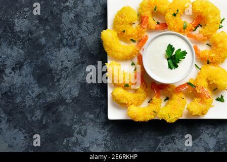 Nahaufnahme von gebratenen Garnelen mit Sauce auf weißem Teller über blauem Stein Hintergrund mit freien Text Raum. Draufsicht, flach liegend Stockfoto