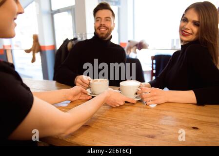 Freundlicher Barkeeper, der den Gästen Espresso im Inneren eines modernen Coffee Shops serviert. Stockfoto