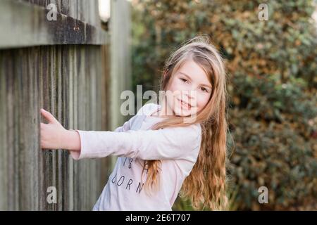 Junges Mädchen hält an einem Zaun im Hinterhof Stockfoto