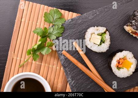 Sushi auf Schiefer auf Bambus und Essstäbchen oben Stockfoto