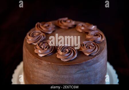 Köstliche Schokoladenkuchen mit Ganache Blumen auf einem rustikalen dekoriert Holzhintergrund Stockfoto
