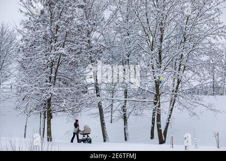 Vilnius, Litauen, 28. Januar 2021. Mutter mit Kinderwagen geht im verschneiten Park Stockfoto