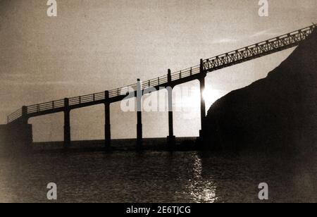 Ein Sonnenaufgangsfoto der ehemaligen Spa Ladder Brücke in Whitby, North Yorkshie (UK), die einst den East Pier mit dem East Cliff in der Henrietta Street (Haggelythe) verband. Eine Reihe von provisorischen Verbindungen verband die beiden im Laufe der Jahre (einschließlich einer tatsächlichen Leiter). Alle wurden durch einen durchgehenden Damm ersetzt, der breit genug ist, um von Einsatzfahrzeugen genutzt zu werden. Im Laufe der Jahre wurden Abschnitte der Brücke hinzugefügt, um mit der ständigen Erosion der Klippen durch schwere Wellen zu bewältigen. Stockfoto