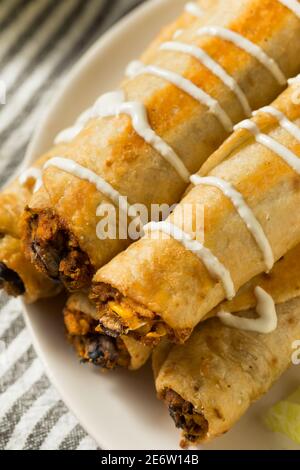 Hausgemachte mexikanische Chicken Flautas mit Crema und Salat und Tomaten Stockfoto