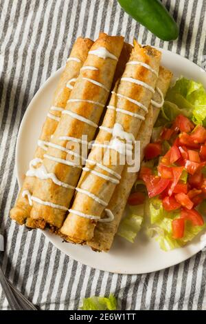 Hausgemachte mexikanische Chicken Flautas mit Crema und Salat und Tomaten Stockfoto