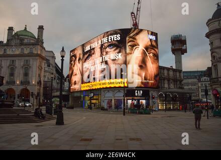 Abendansicht des Piccadilly Circus, London, mit der neuen Coronavirus-Kampagne, 29. Januar 2021. Die Regierung hat eine starke neue Kampagne gestartet, um die Menschen zu überzeugen, zu Hause zu bleiben, während die Nation darum kämpft, die Pandemie unter Kontrolle zu halten. Stockfoto