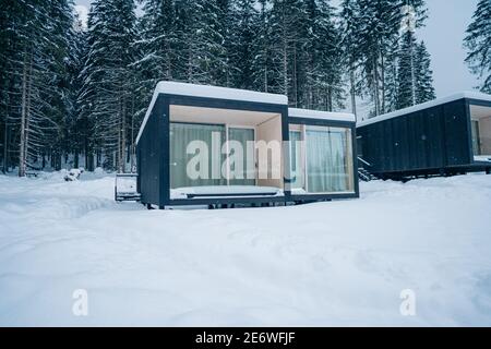 Moderne Holzhütte und schneebedeckte Bäume im Winter Finnland Lappland. Abgeschiedenes kleines Haus. Privates Haus in der Nähe von Wald. Landhaus. Stockfoto