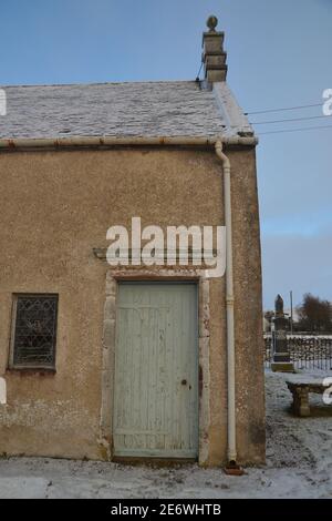 Eine alte hölzerne Tür mit blassgrüner Farbe auf der Seite der alten Steinkirche in Kildonan im Winter, Schottische Highlands, Großbritannien. Stockfoto