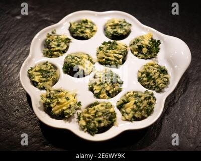 Ein Dutzend Schnecken auf weißem Teller mit Schneckenbutter. Perspektivische Ansicht. Stockfoto