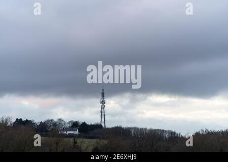 Große 5G Handy-Satellitensender Turmmast neben Zu den Häusern am Hang launisch dunkel bewölkt grau stürmisch Himmel Verursacht Silhouette Stockfoto