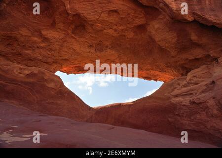 Kleiner Bogen oder kleine Felsenfensterformation in der Wadi Rum Wüste, blauer Himmel durchgesehen Stockfoto