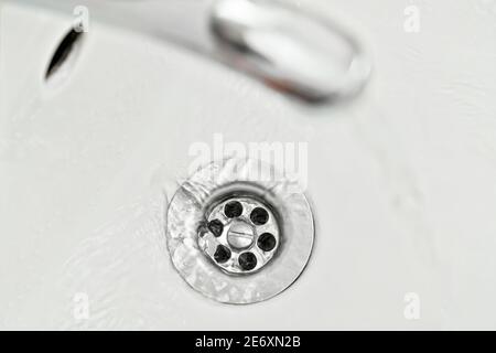 Wasser fließt von Wasserhahn zu Waschbecken, Blick von oben, Detail auf silberne Hahnloch Stockfoto