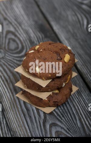 Haferflocken Kekse mit Erdnüssen und Schokolade. In einer Säule gefaltet und mit Papier ausgelegt. Auf Kiefernbrettern. Stockfoto