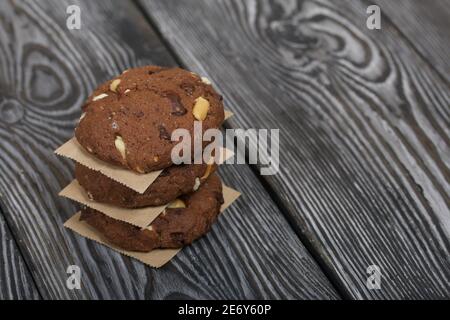 Haferflocken Kekse mit Erdnüssen und Schokolade. In einer Säule gefaltet und mit Papier ausgelegt. Auf Kiefernbrettern. Stockfoto
