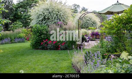 Ruhige Szene einer japanischen Zierweide, in voller Blüte mit Rosen, Minze, Hortensien in einem Garten im Mittleren Westen. Stockfoto