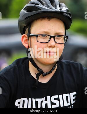 Junge gut aussehende fair gehäutet preteen Junge trägt ein schwarzes Fahrrad Helm und dunkle Brille sehen zuversichtlich für den Start Das Rennen Stockfoto