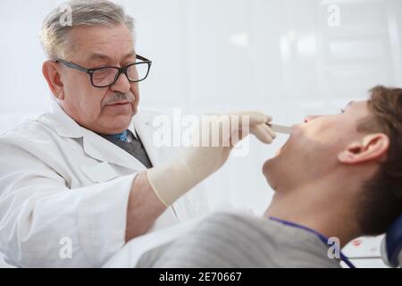 Nahaufnahme eines älteren männlichen Zahnarztes, der Zähne untersucht Ein Patient Stockfoto