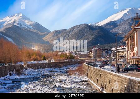 Bansko, Bulgarien - 28. Januar 2021: Fluss Glazne in der bulgarischen Stadt, Hotelhäuser und Schnee Pirin Berge Stockfoto
