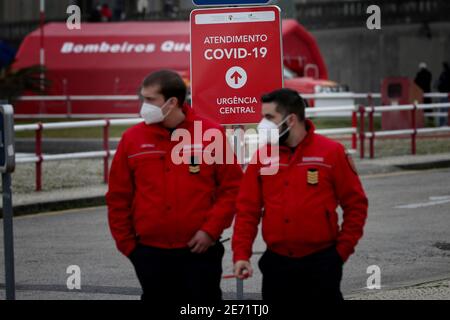 Lissabon, Portugal. Januar 2021. Feuerwehrleute mit Gesichtsmasken gehen am 29. Januar 2021 an einem Covid-19-Schild am Santa Maria Hospital vorbei. Portugal meldet täglich neue Aufzeichnungen über COVID-19-Todesfälle und Krankenhausaufenthalte, da eine jüngste Pandemie-Zunahme unvermindert anhält. Quelle: Pedro Fiuza/ZUMA Wire/Alamy Live News Stockfoto