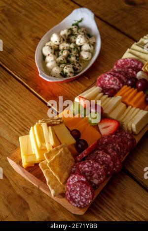 Italienische Wurstplatte mit Crackers Käse und Salami serviert Holzdiele mit roher Rindenkante Stockfoto