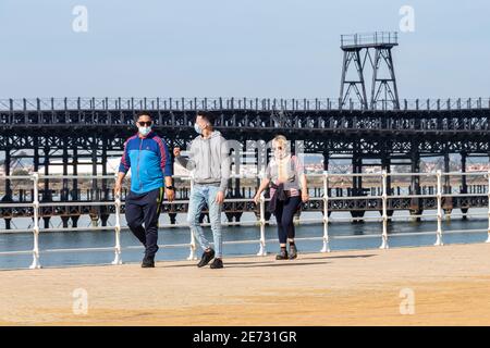 Huelva, Spanien - 27. Januar 2021: Menschen, die an der Promenade von Huelva spazieren, während des Alarmzustandes und der Quarantäne i Schutzmasken oder medizinische Gesichtsmasken tragen Stockfoto