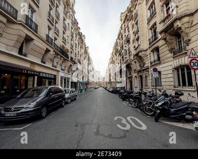 Paris, Frankreich - 13. Okt 2018: Perspektivischer Blick über die leere Straße der Rue de Vaugirard im Zentrum von Paris mit geparkten Autos und Motorrädern und Le Baribal Restaurant auf der rechten Seite 30 kmh Straßenschild Stockfoto