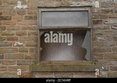 Alte Fensterrahmen mit gebrochenem Fenster auf einem alten Stein gebaut Bauernhof in England, Großbritannien genommen Stockfoto