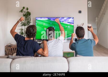 Eine Gruppe von Freunden, die ein Spiel im fernsehen ansehen, um die zu feiern Sieg ihres Teams Stockfoto